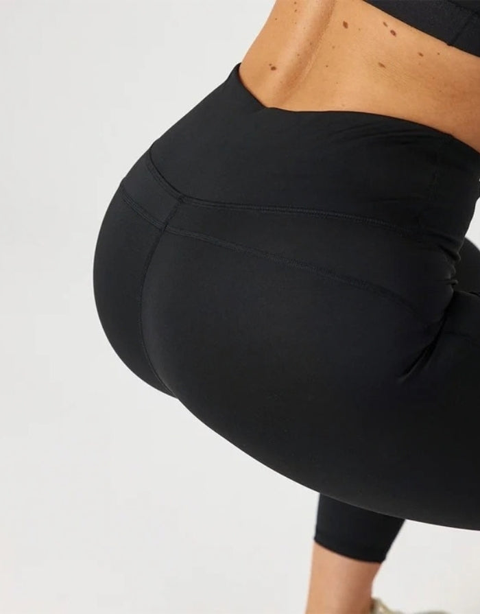 High-Waist-Leggings von SNOCKS mit hohem Bund aus flexiblem, blickdichtem Material mit recyceltem Polyester am Model von hinten im Detail 