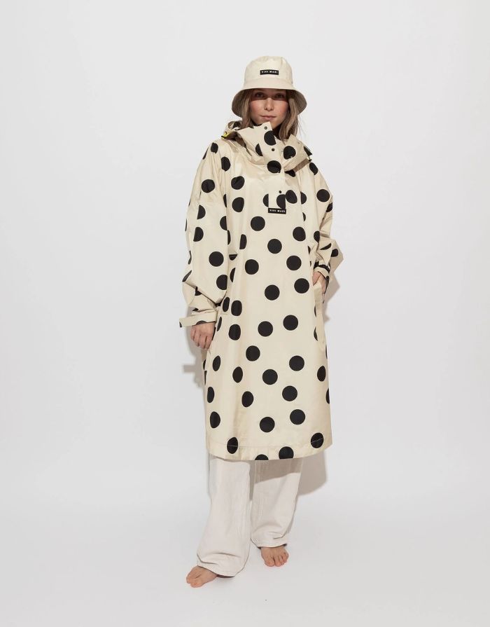 Raincoat Bold Stripes Dots Black/Sand von VIVI MARI: Langer, wasserdichter Regenmantel im Streifen-Design, oversized geschnitten mit Kapuze, Knopfleiste, Klettverschluss-Manschetten und praktischen Taschen – nachhaltig aus recyceltem Polyester gefertigt.