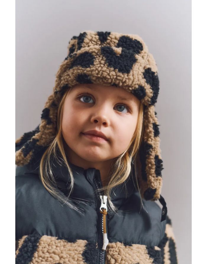 Pilotenmütze Teddy Bravo von Liewood in Mega Leo/Oat Mix aus 100% recyceltem, OEKOTEX®-zertifiziertem Polyester, mit Ohrenklappen und Kinnverschluss.
