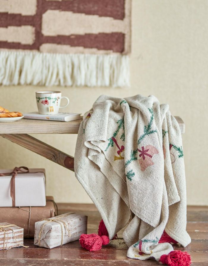 Bloomingville Decke Yule Natur aus recycelter Baumwolle mit Weihnachtsmotiv über einer Bank