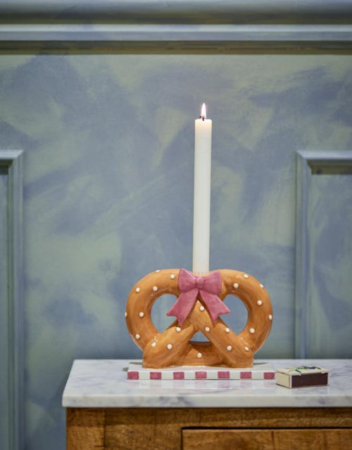 Brauner Pretzie Kerzenhalter von Bloomingville aus handbemalter Keramik in Brezelform mit weißen Punkten und rosa weiß gestreiftem Sockel.
