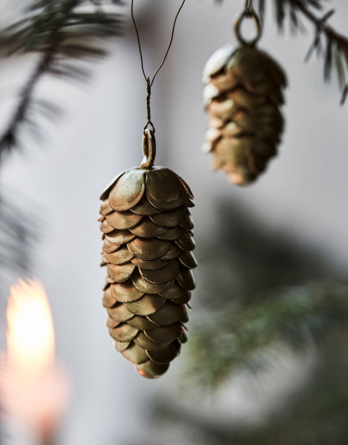 Zwei goldene Cone Tannenzapfen Anhänger von House Doctor aus Eisen in unterschiedlichen Größen im Detail am Baum